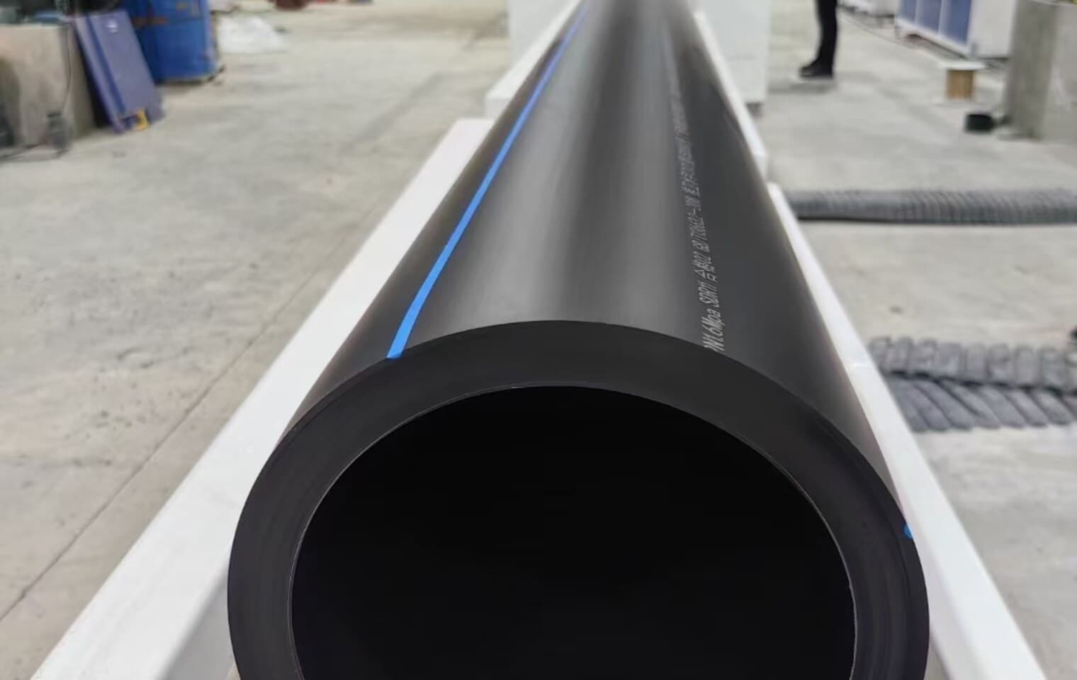 The cut end of a heavy-wall PE pipe, printed with its grade and dimensions along the barrel