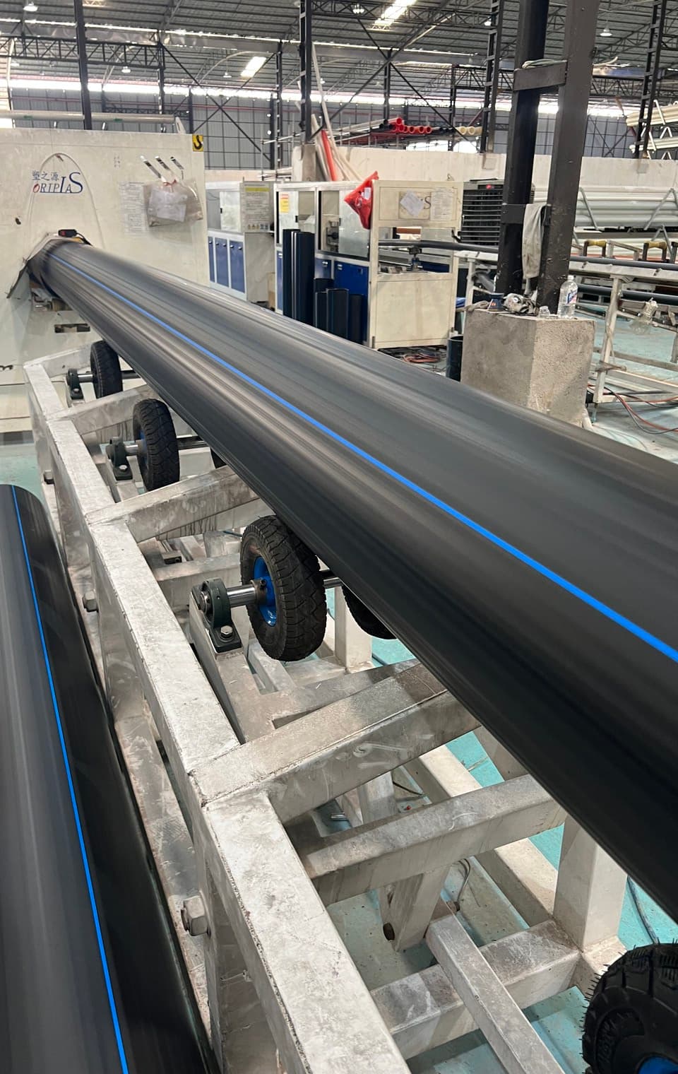 A large-diameter PE pipe on the roller bed in the production hall