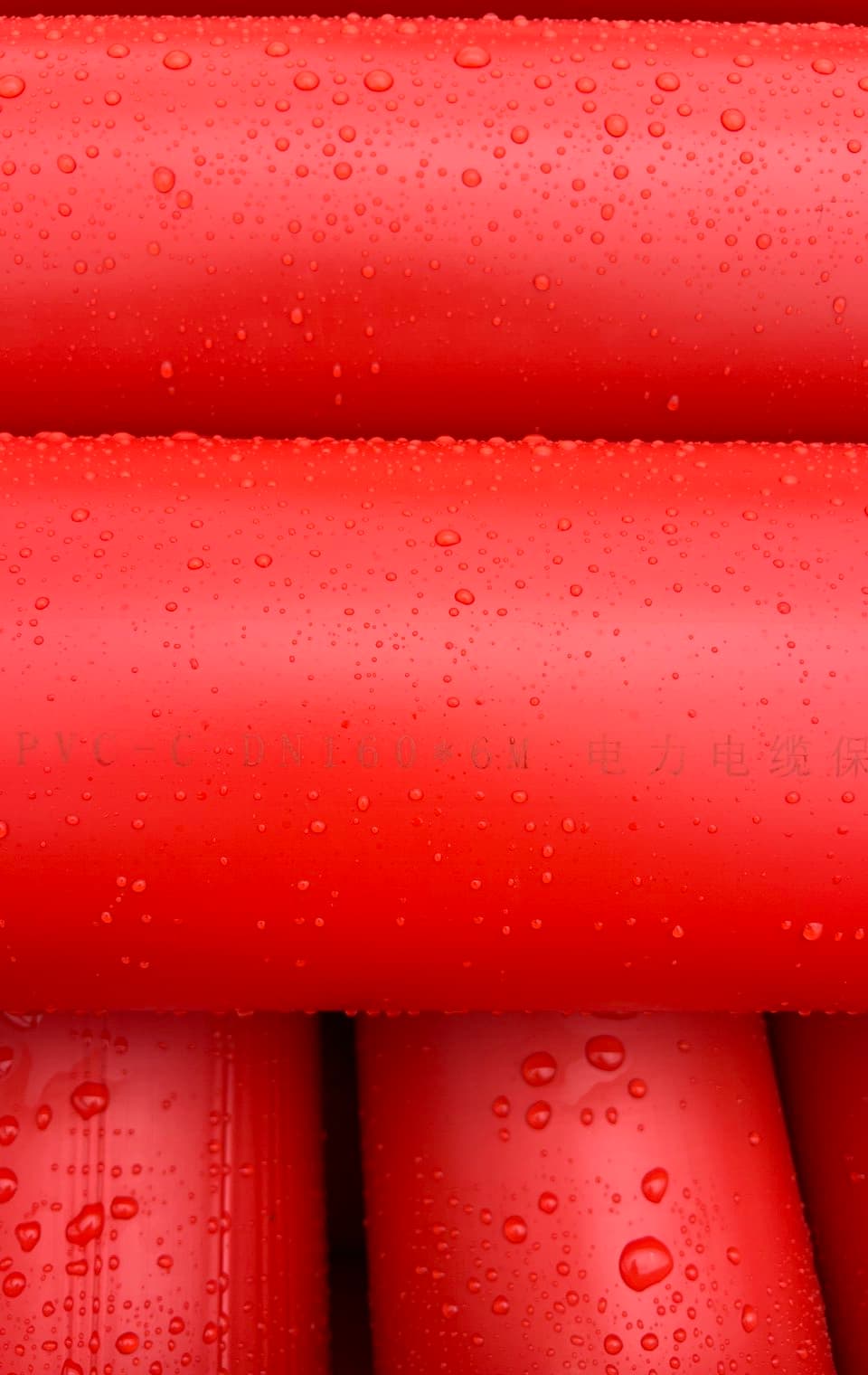 Red conduit close up, water beading on the surface after rain in the yard