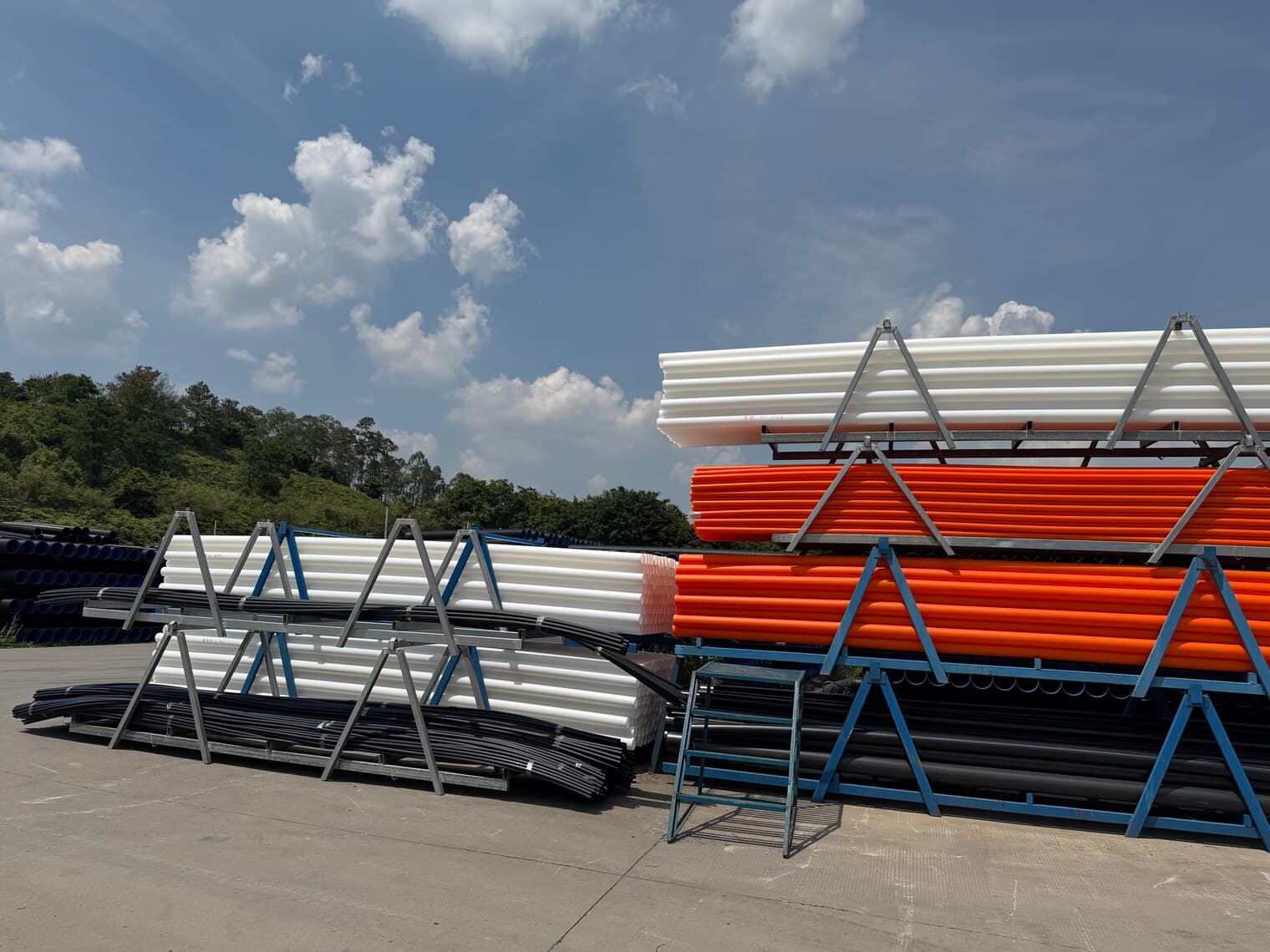 Racks of pipe in different colours — orange conduit, white and black PE — kept apart by product type