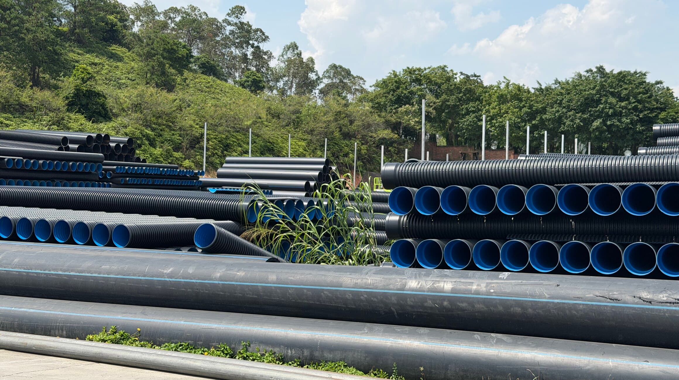 Rows of double-wall corrugated pipe in the yard, the blue inner wall visible at every socket