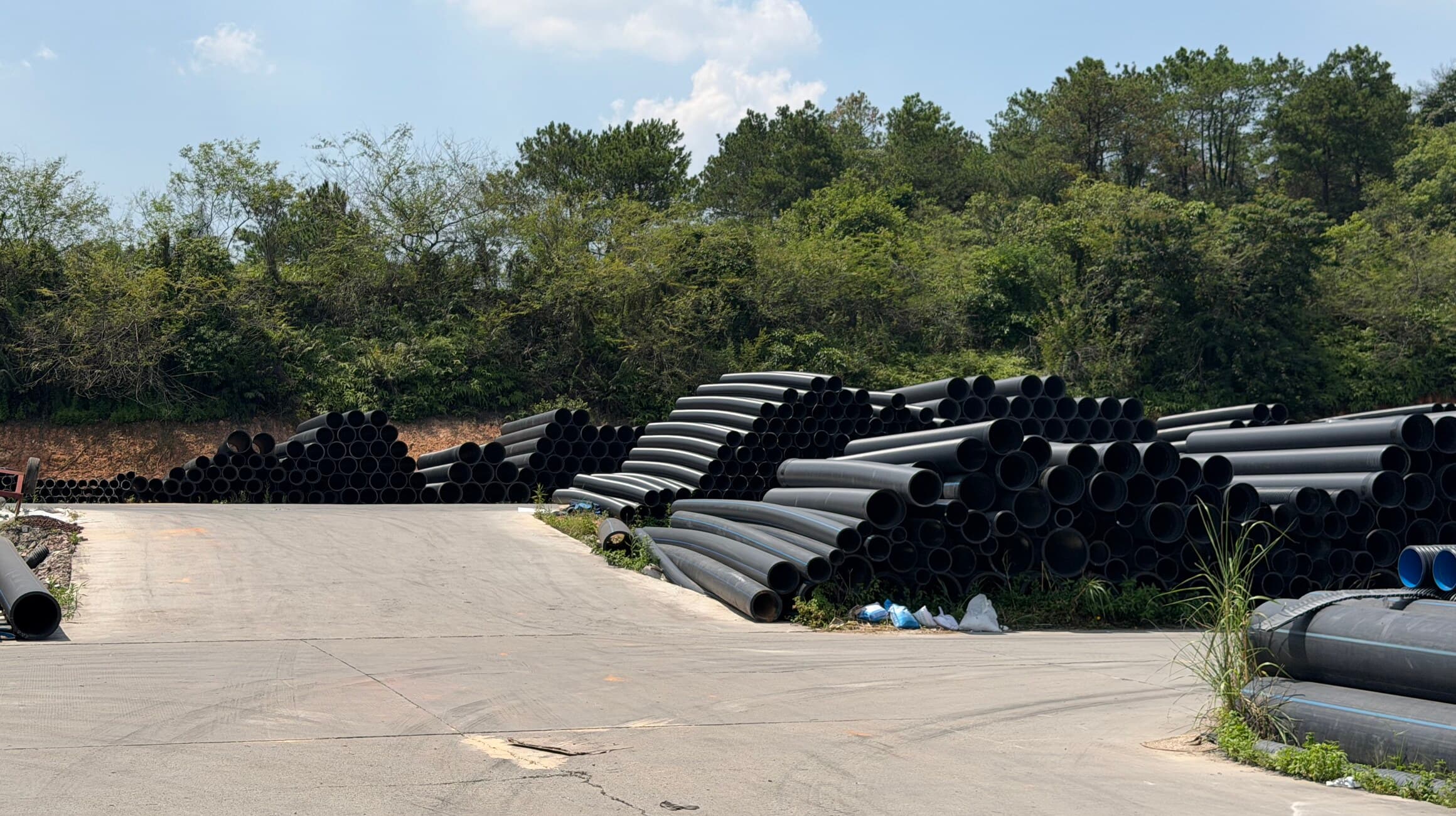Double-wall corrugated pipe stacked along the yard road, sorted by diameter