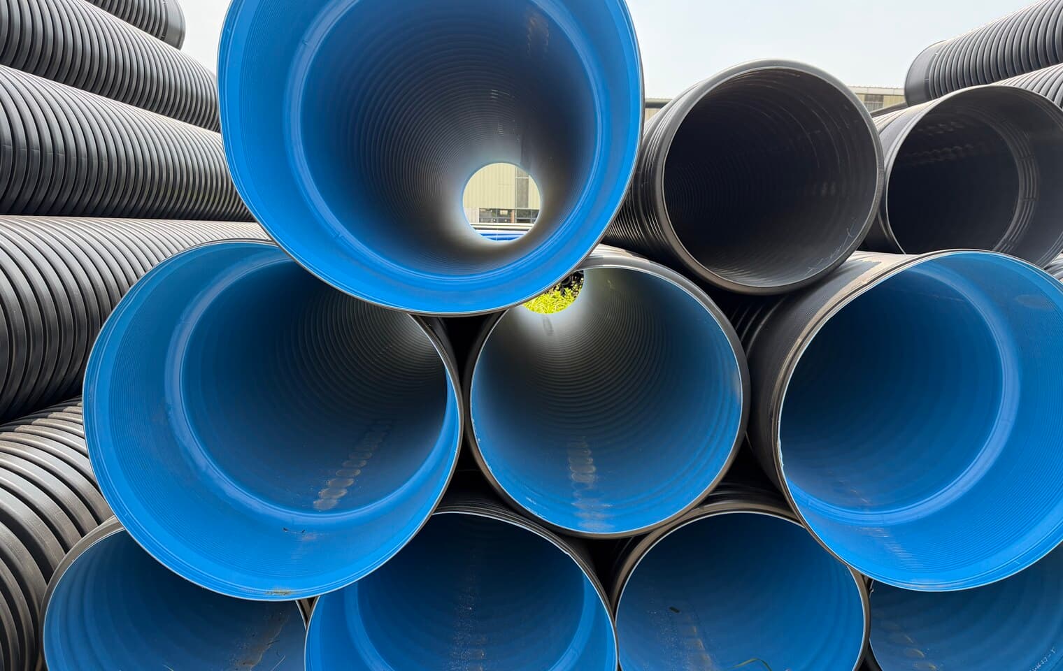 Double-wall corrugated pipe seen end-on, the smooth blue bore inside the ribbed black outer wall