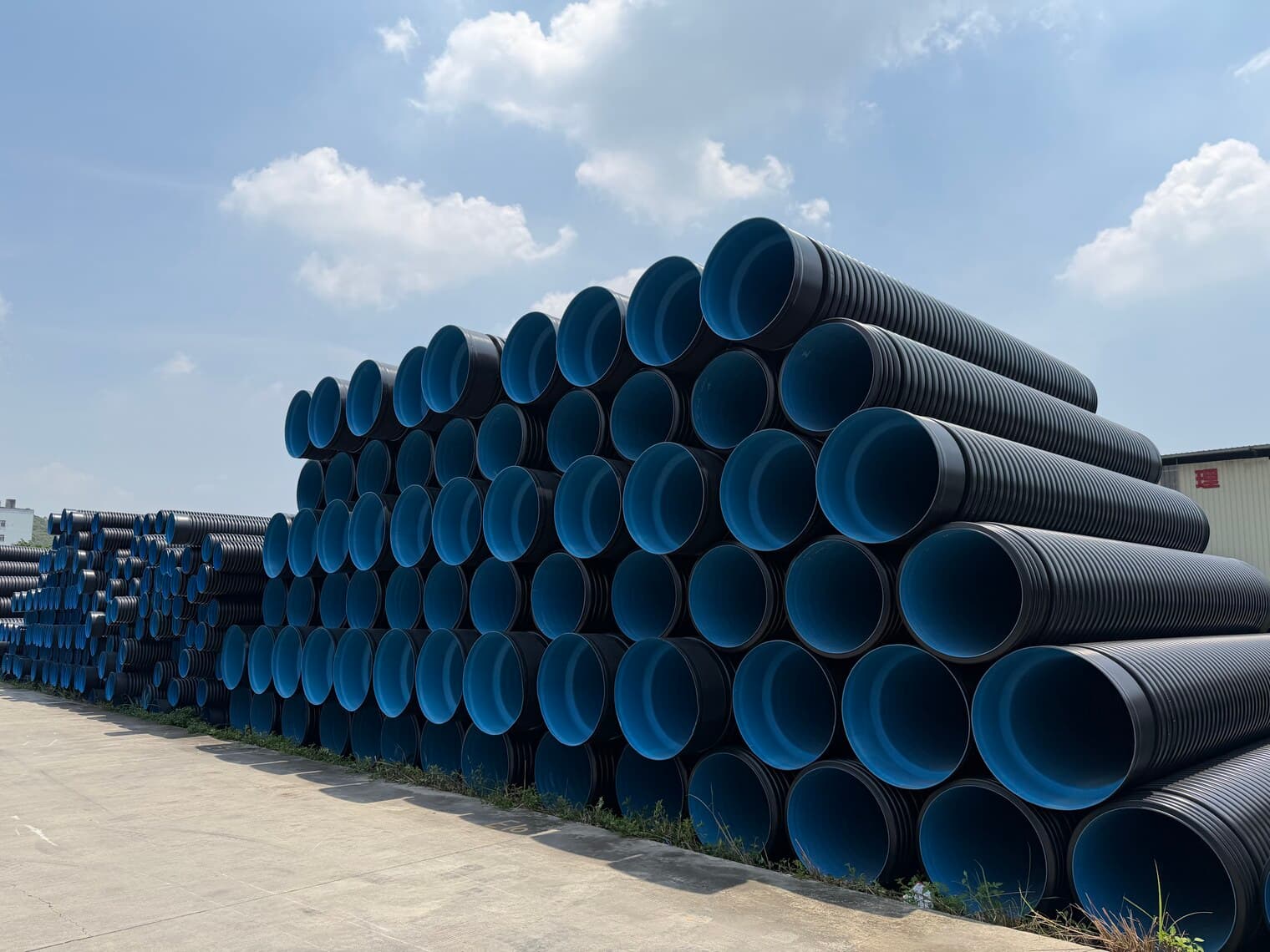 A stack of double-wall corrugated pipe, the blue inner wall visible at every socket