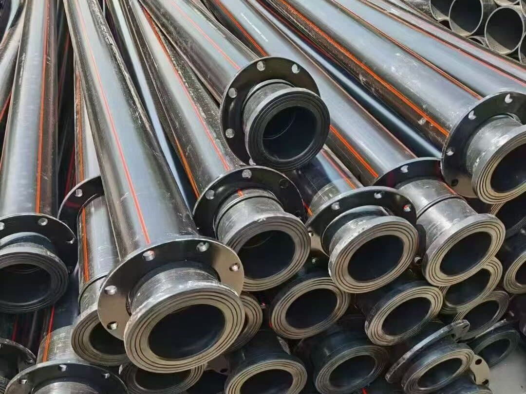Prefabricated HDPE spools with stub ends and backing flanges, orange-striped, stacked in the yard before dispatch