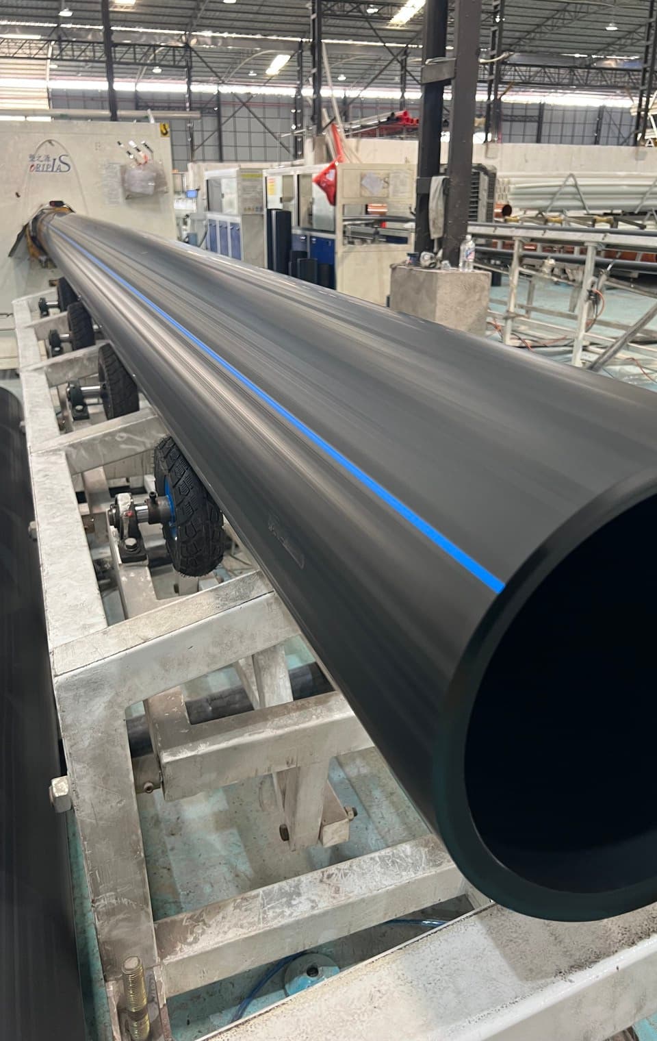 A large-diameter PE100 pipe on the roller bed, the bore wide enough to show the full wall thickness