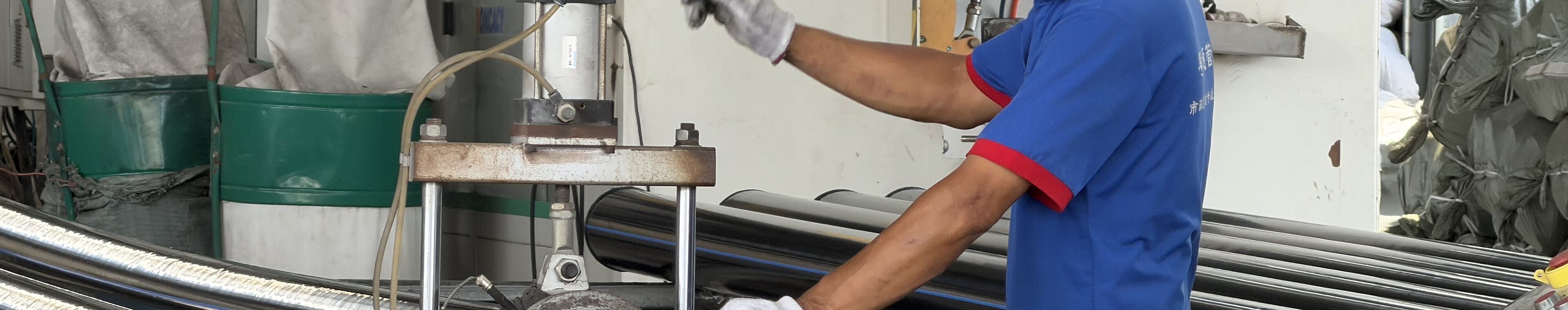 An operator in a hard hat facing a pipe end on the shop machine before welding