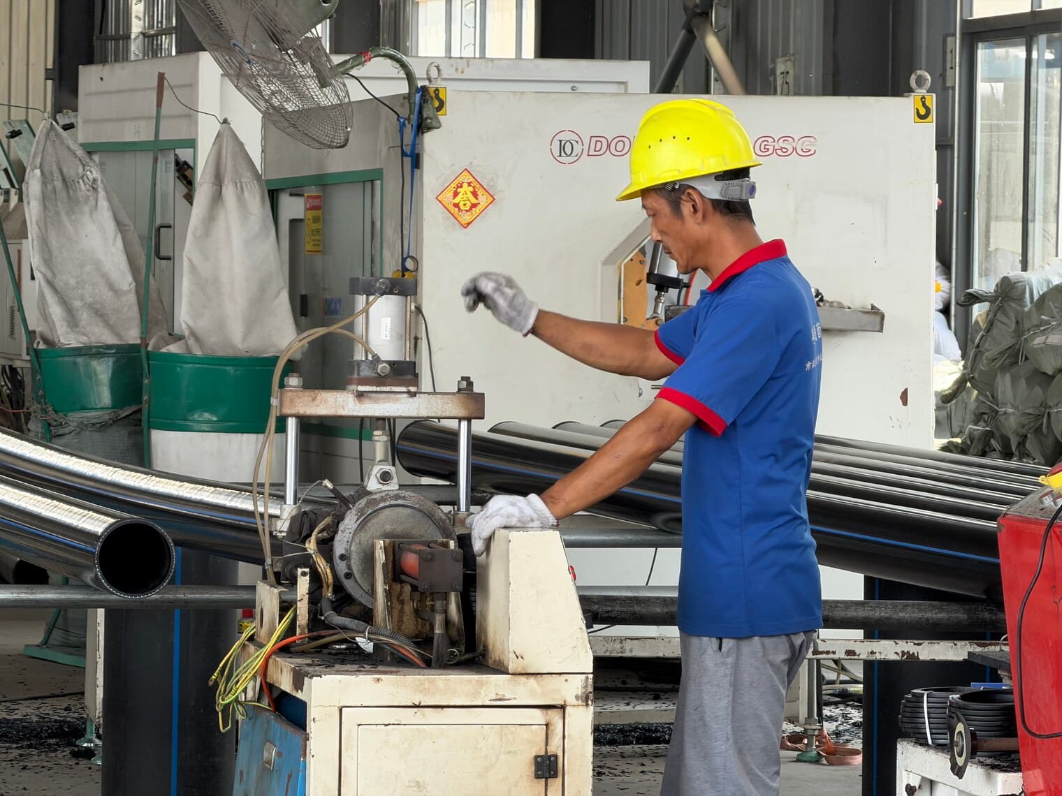 An operator at the cut-off station, squaring the ends of a run of PE100 pipe