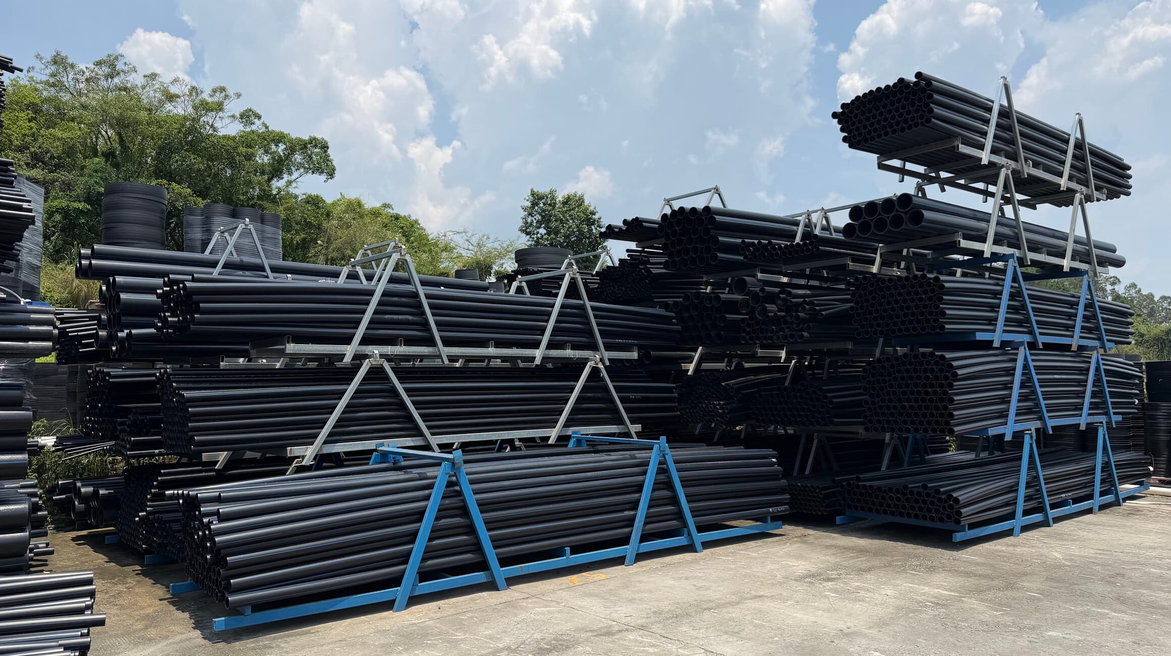 A wide view across the stock yard, rows of finished PE100 pipe in front of the production halls