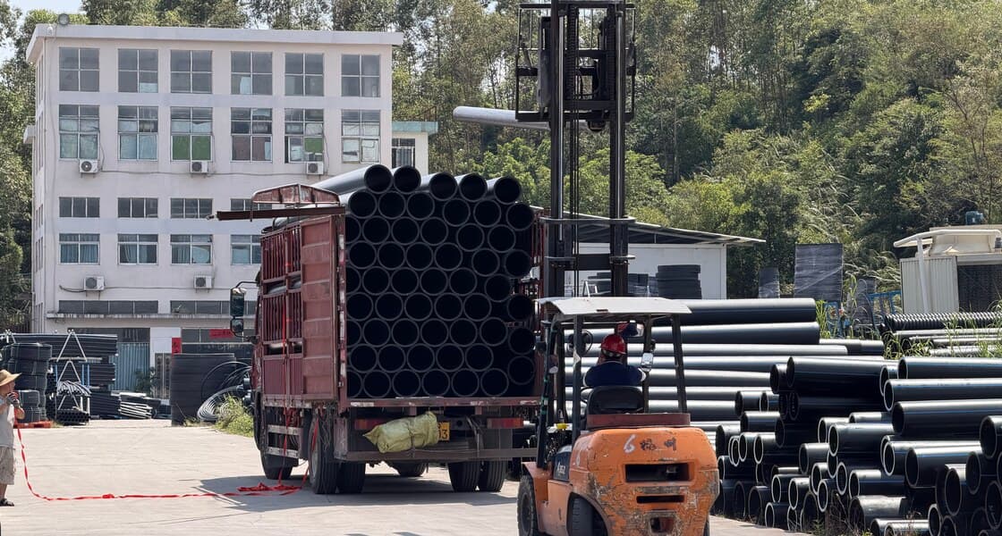 A flatbed truck being loaded with bundled HDPE pipe by forklift in the despatch area