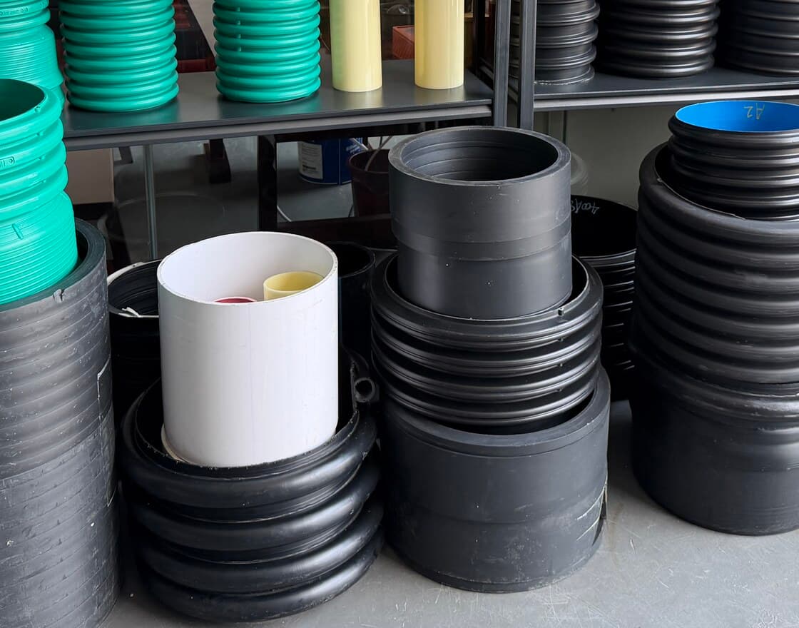 A sample display of moulded HDPE products — corrugated pipe sections, chamber bases and pipe stubs