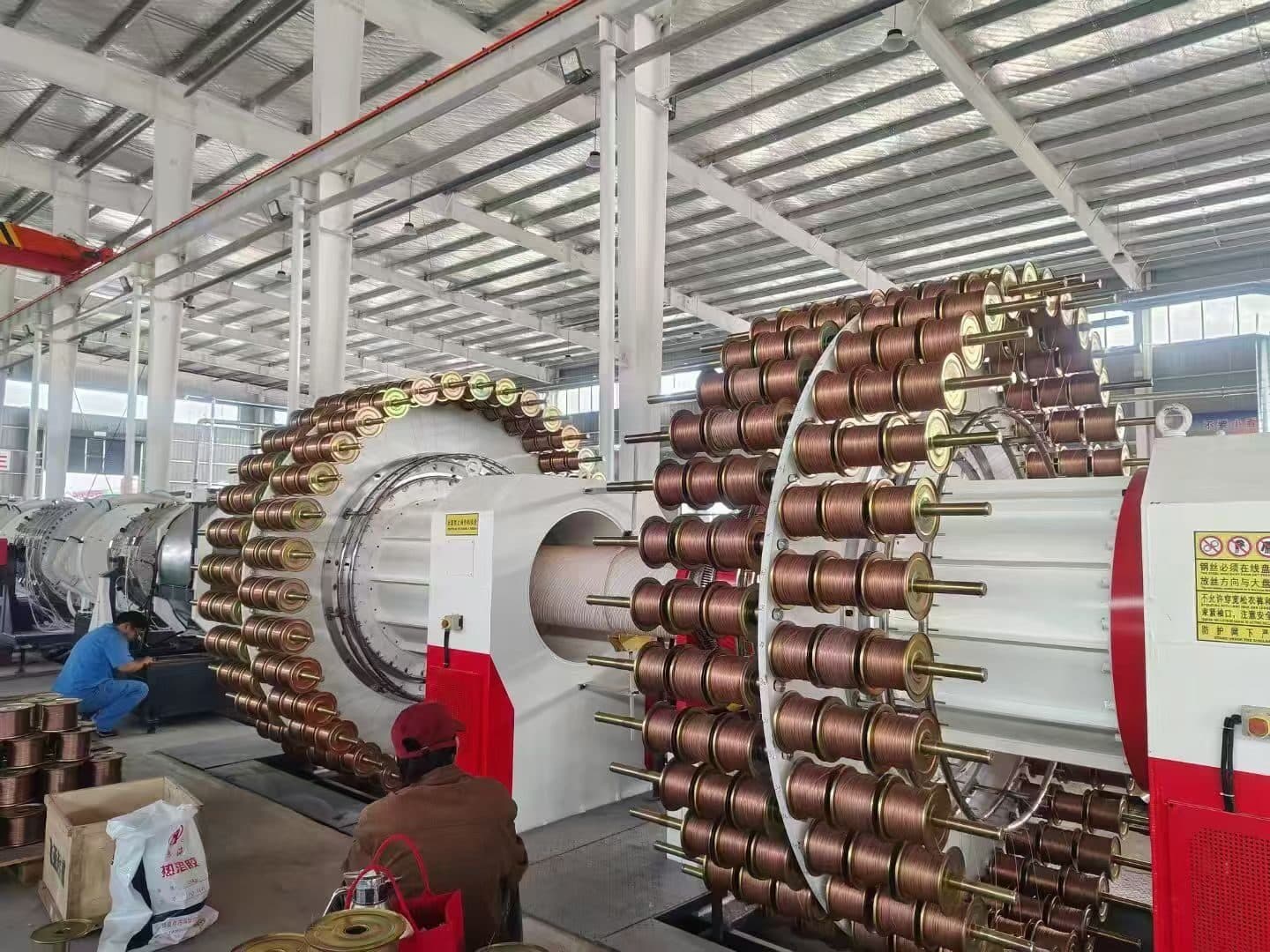 The steel-wire winding machine that forms the reinforcing mesh, with copper-coloured wire spools feeding the mandrel