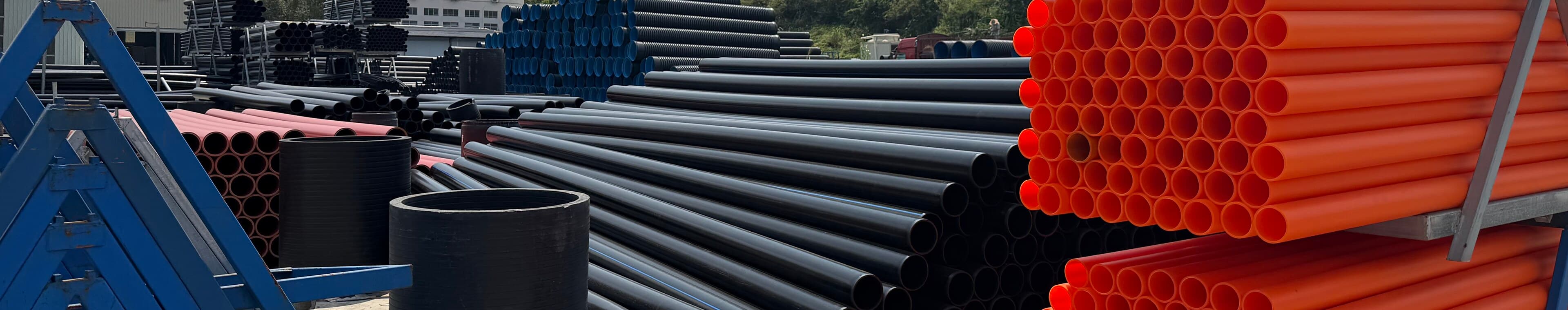 Stacks of black, blue-lined and orange pipe in the yard, sorted by product type