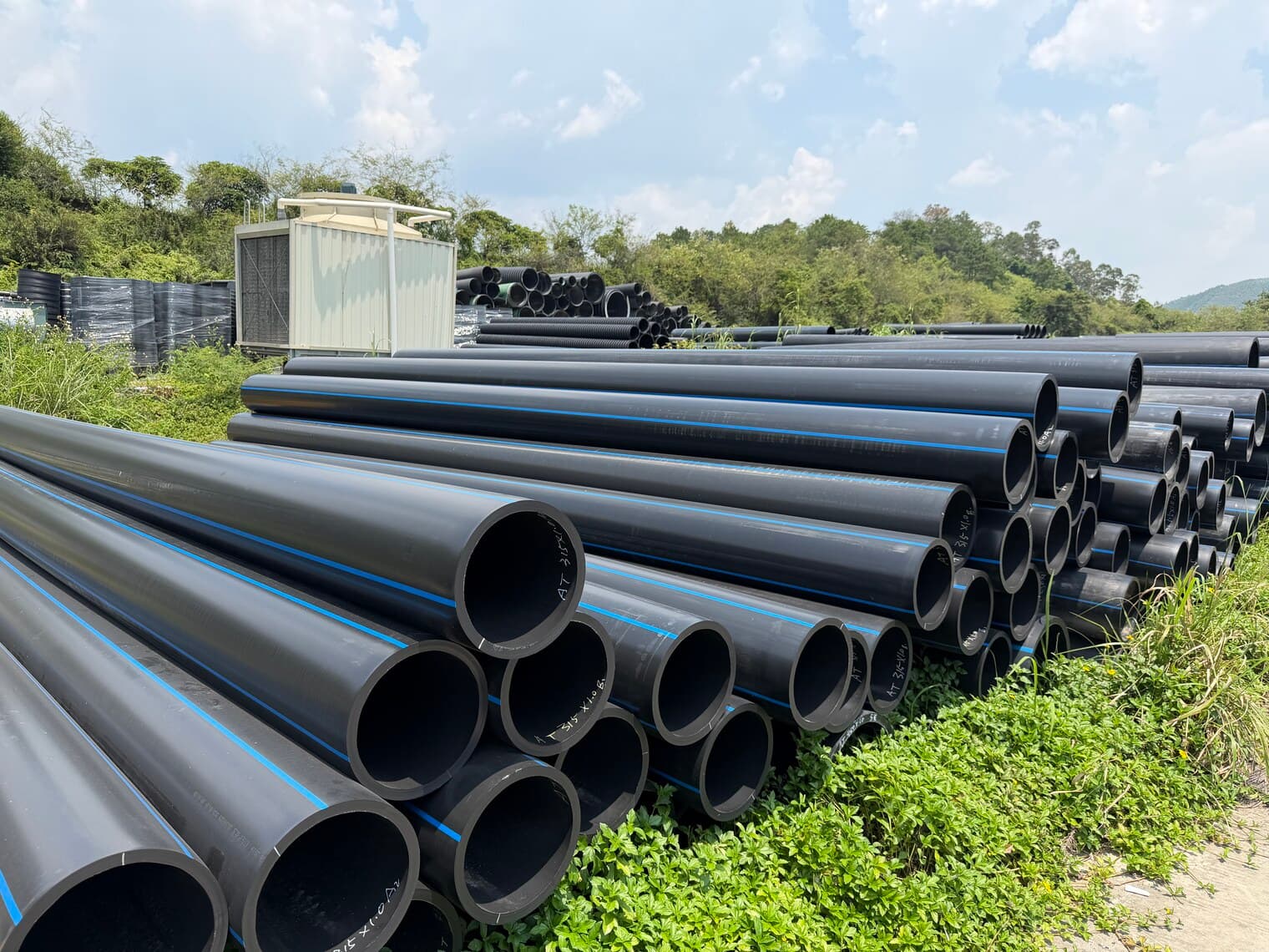 Large-diameter PE100 pipe stacked outdoors, wall thickness visible at the cut ends