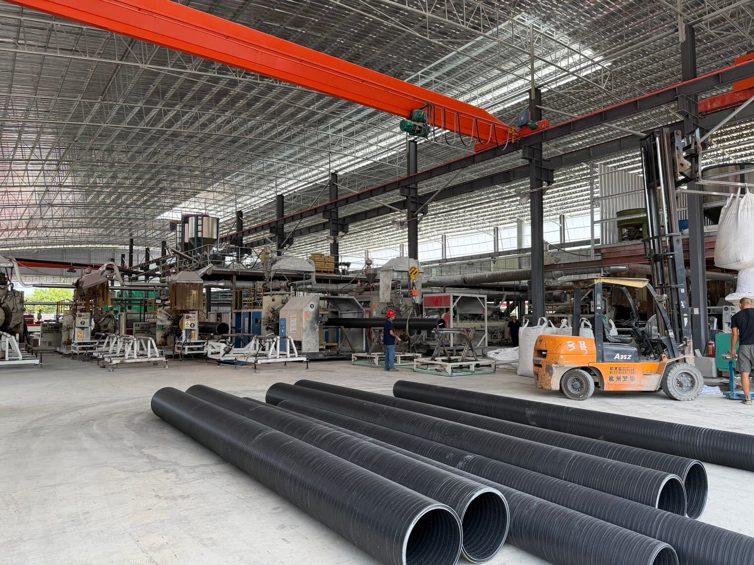 Large-diameter pipe on the workshop floor beside the overhead gantry