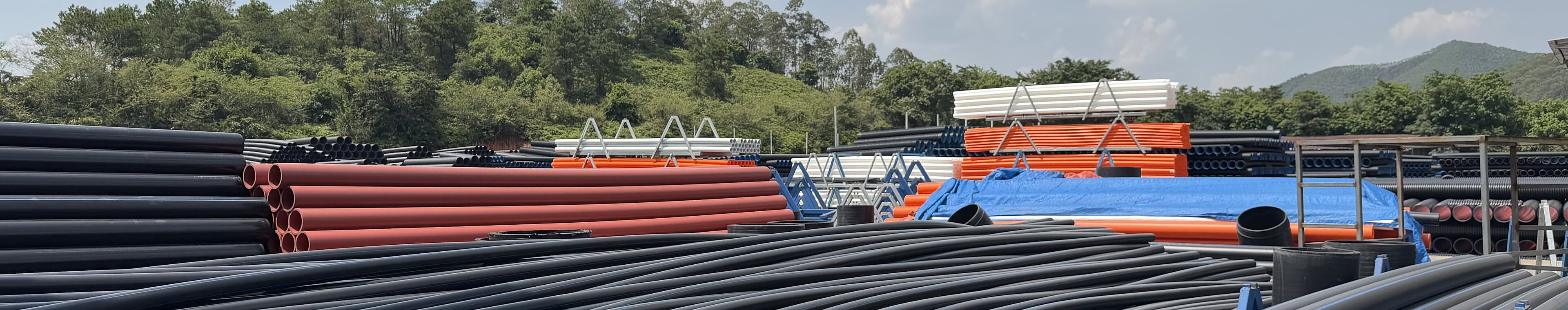Large-bore PE100 pipe and coloured conduit filling the storage yard behind the plant