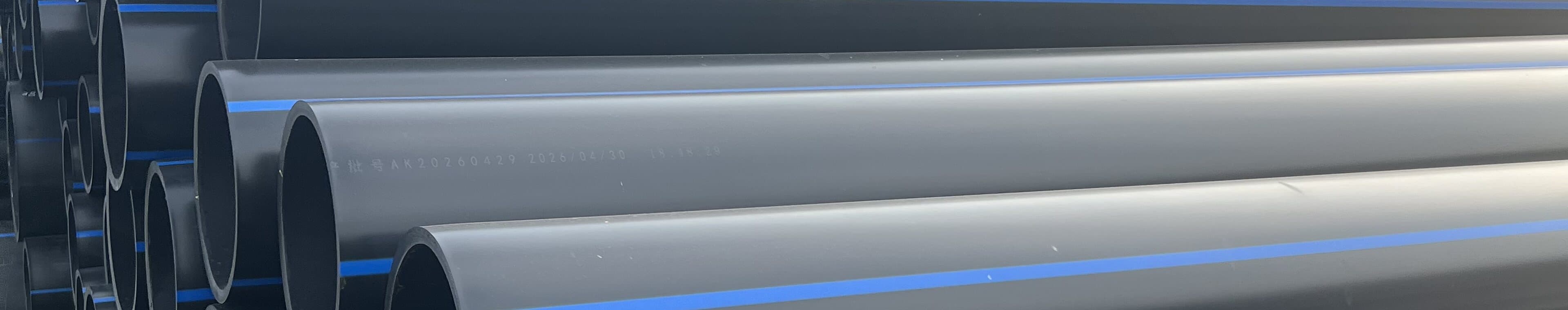 Blue-striped PE100 potable water pipe stacked by diameter in the open yard